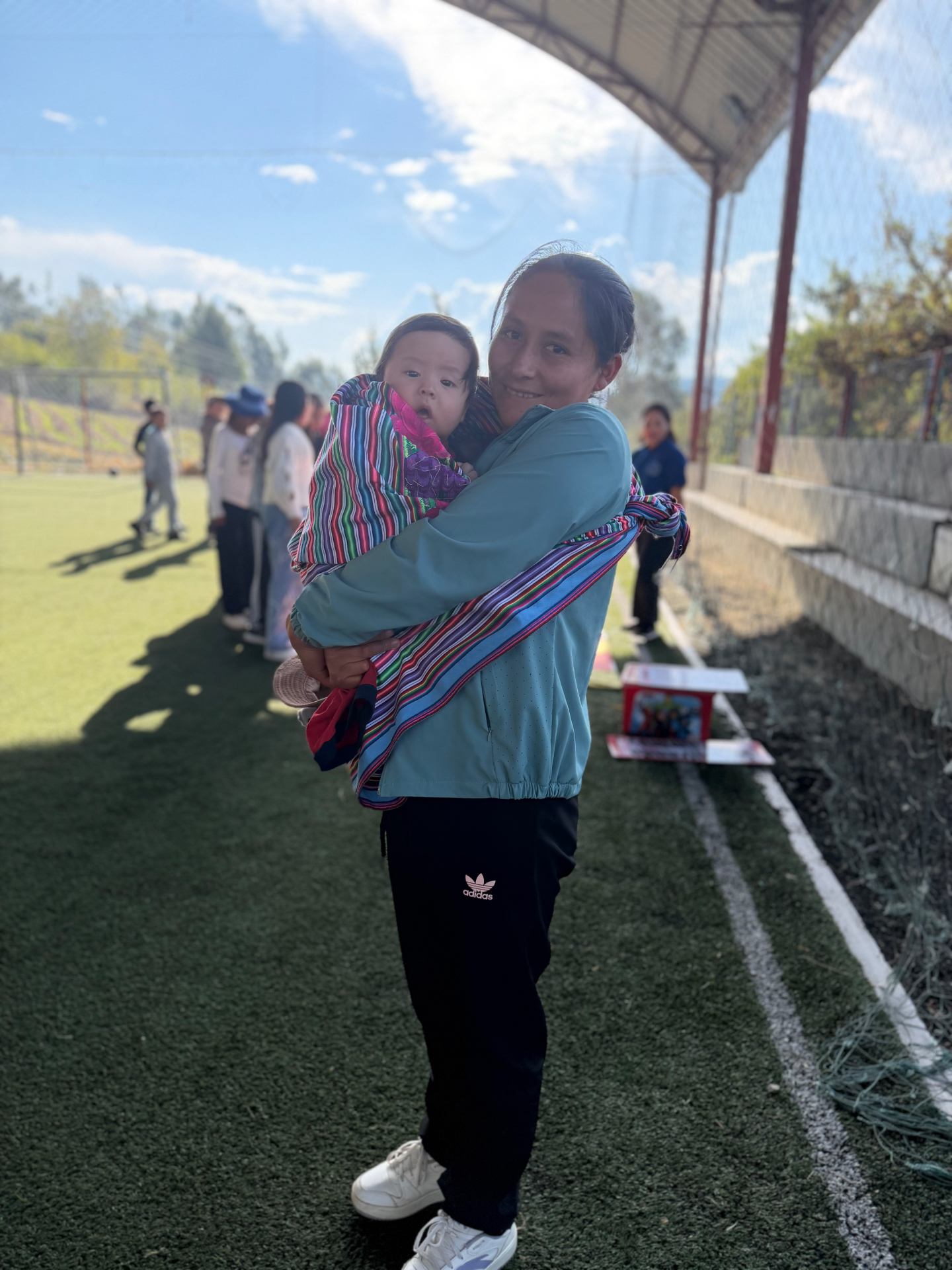 A woman holding a child outdoors during a mission gathering